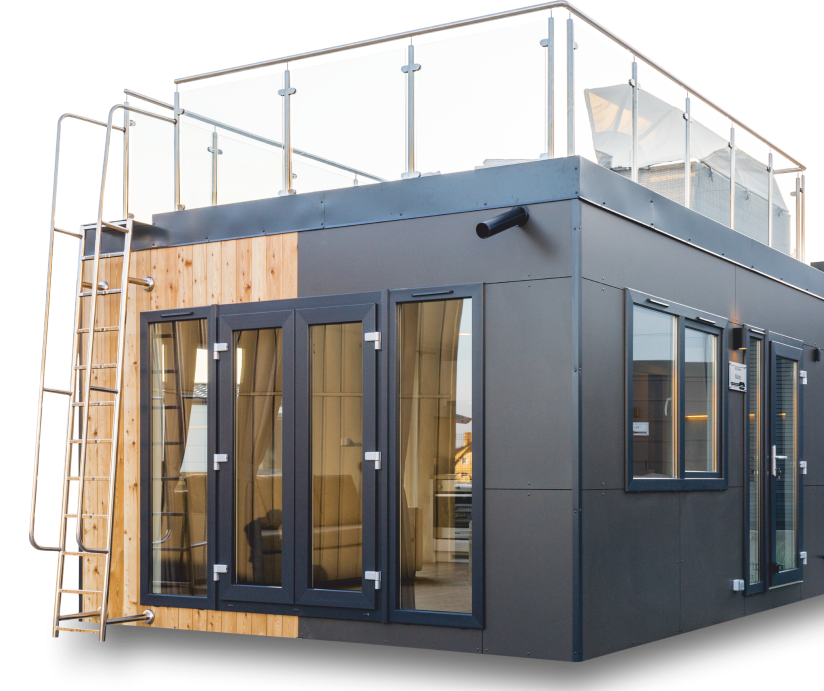 Mobilheim Malta ohne Hintergrund. Die Außenfassade ist eine Kombination von sibirische Lärche Paneelen und Anthrazitfließen. Die Fenster und Türen sind schwarz. Das Haus hat eine Dachterrasse. Die Vorderseite des Hauses hat große Panoramafenster.